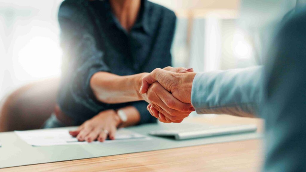 Advisor shaking hands with a client across a table during a meeting